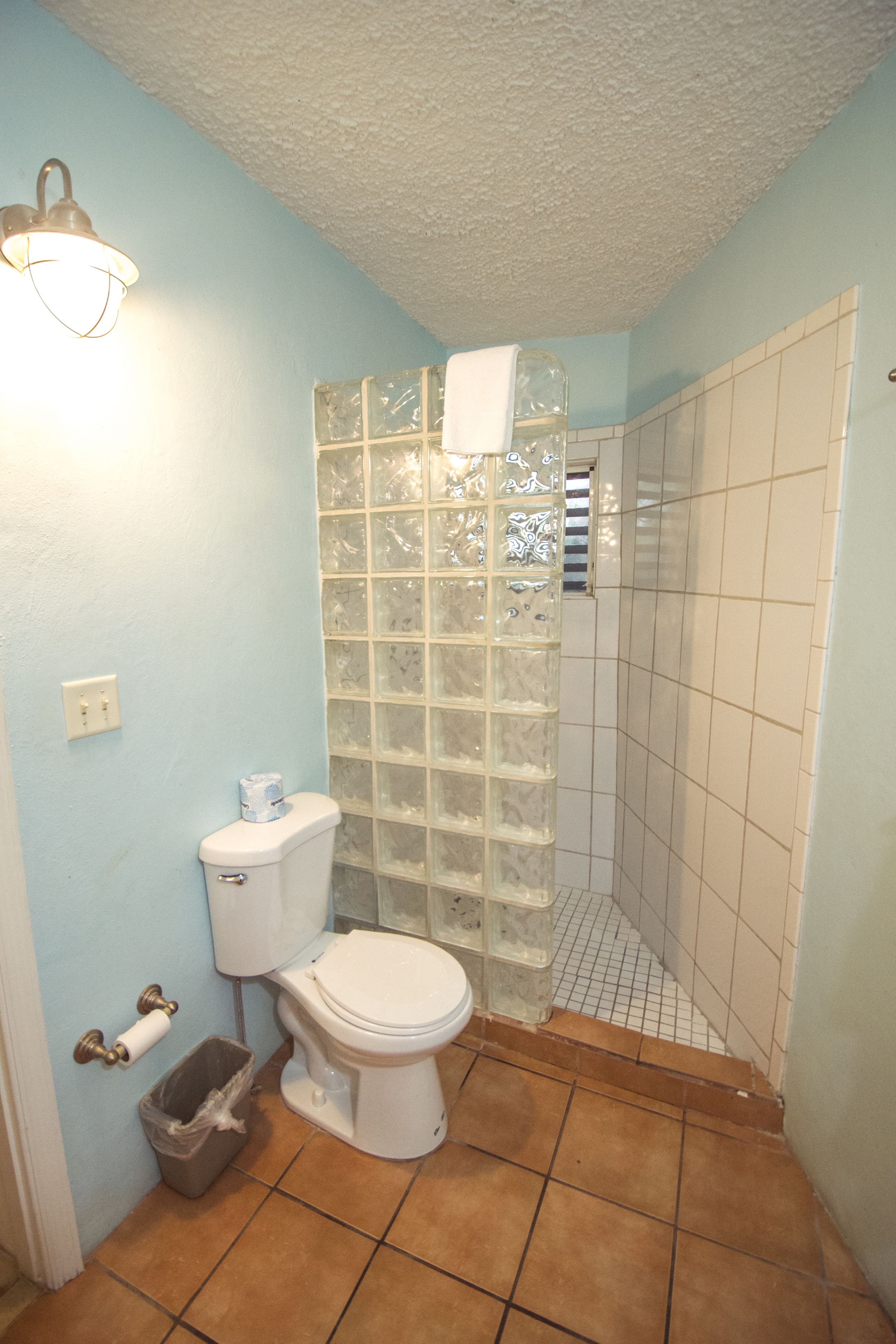Ein Badezimmer mit Toilette, einer Dusche mit Glastür und einem Mülleimer.