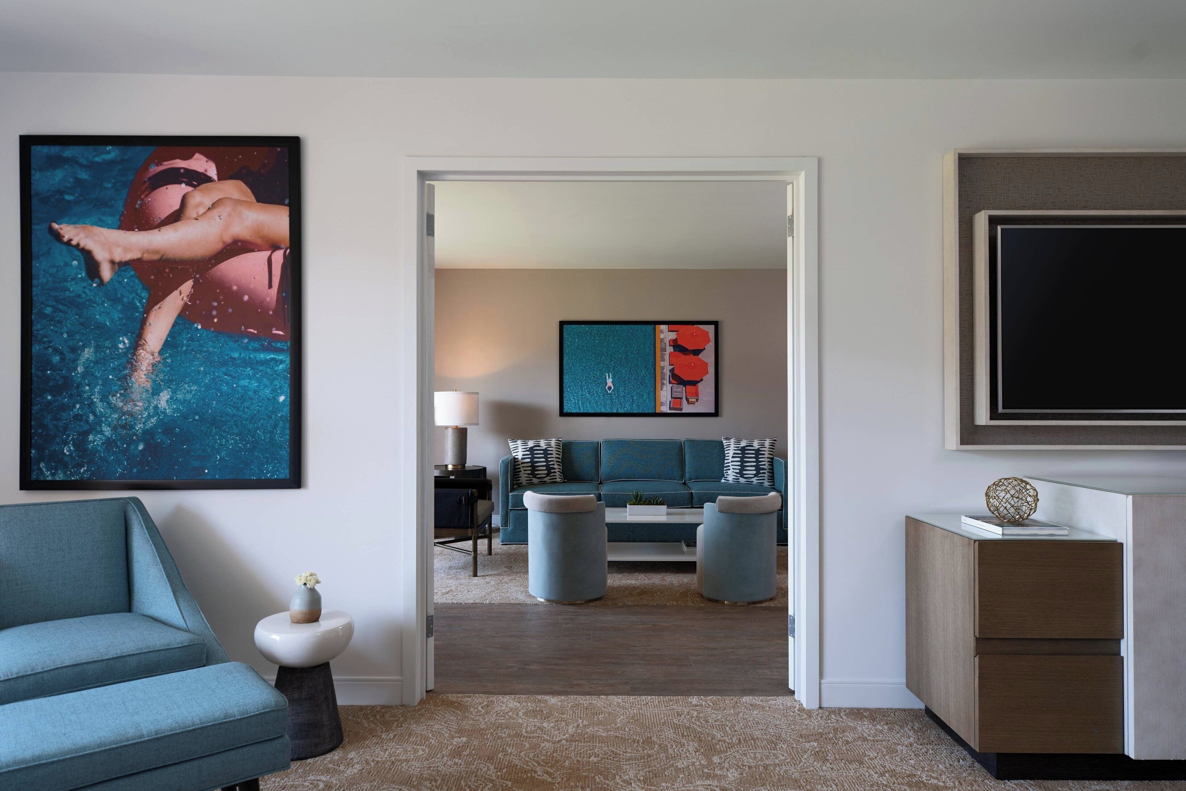 A modern living room with a teal sofa, a coffee table, and a TV on a stand.