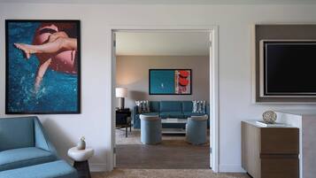 A modern living room with a teal sofa, a coffee table, and a TV on a stand.