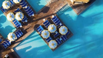 An aerial view of a pool area with sun loungers and umbrellas arranged in a grid pattern.