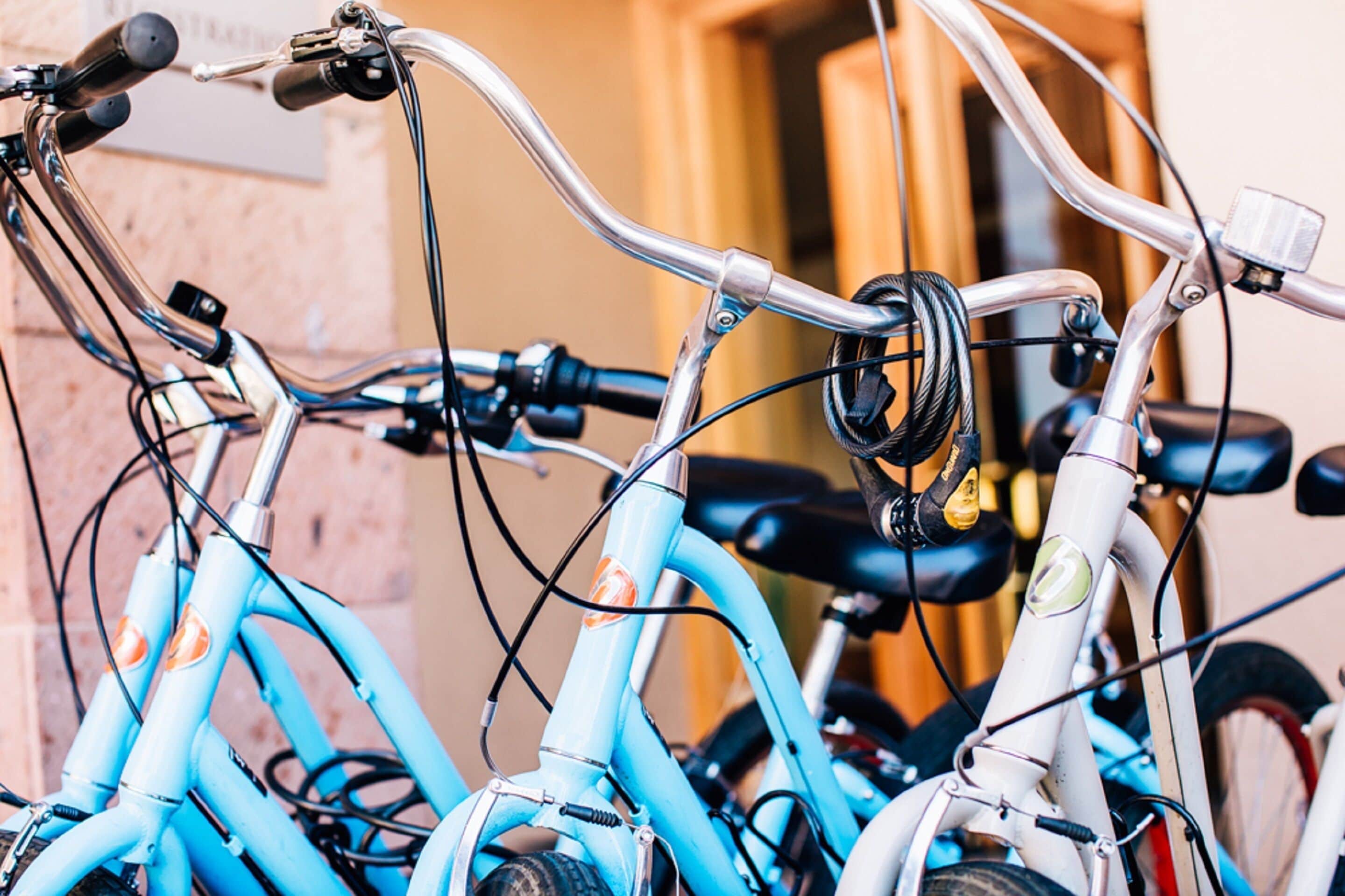 A close-up of a bicycle's handlebars and front wheel, with a background of a wooden door and a wall.