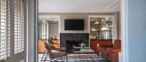 A living room with a fireplace, a flat-screen TV, a sofa, and a dining table.