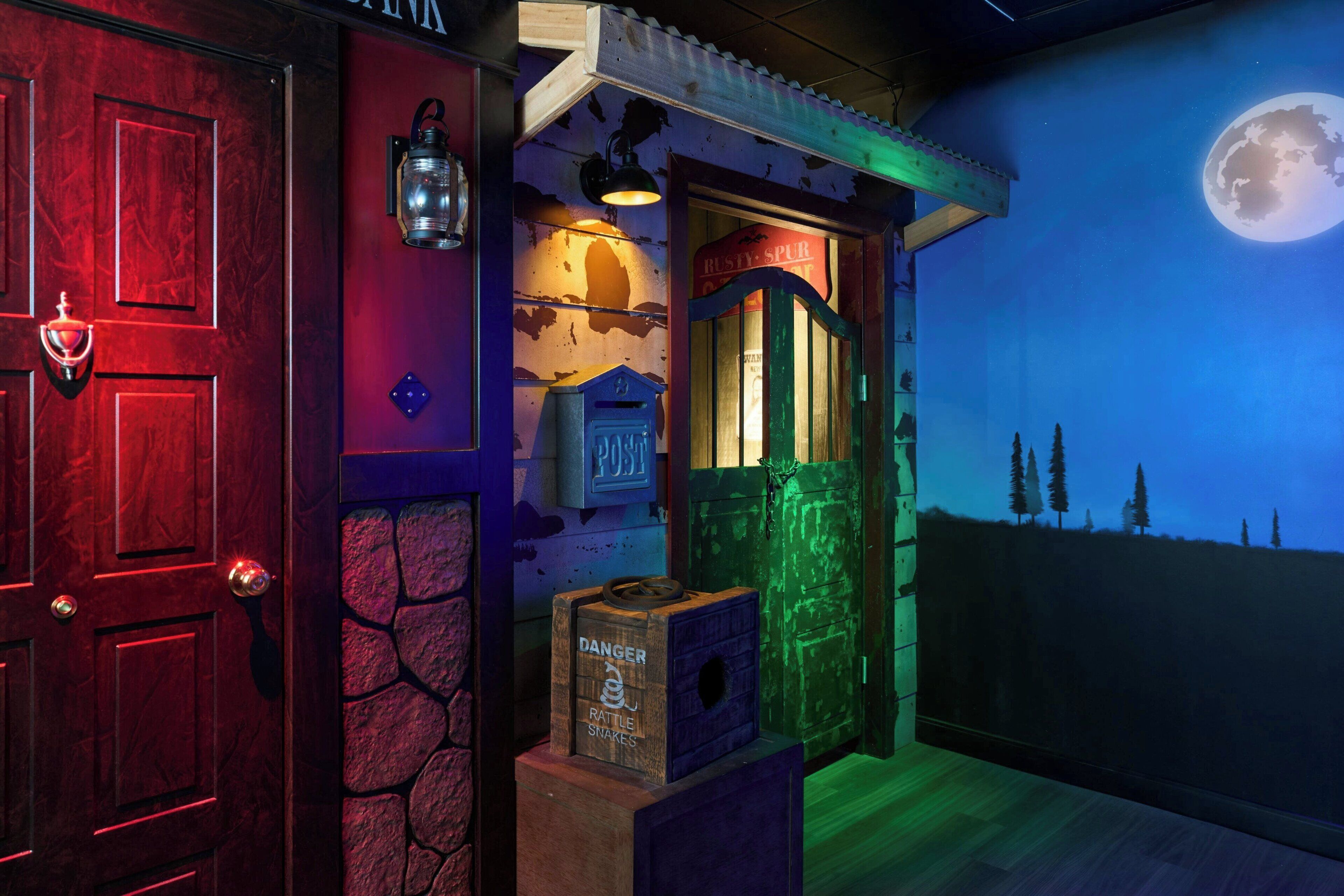 A room with a red door, a mailbox, a wooden box labeled "DANGER RATTLE SNAKES," and a mural of a moonlit landscape.