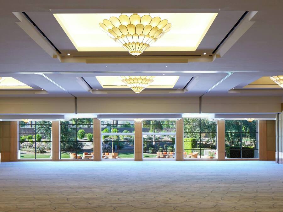 A spacious indoor area with large windows and a ceiling with multiple light fixtures.
