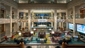 A spacious lobby with multiple seating areas, a bar in the center, and a large screen displaying information. - Renaissance Esmeralda Resort & Spa, Indian Wells (Indian Wells)