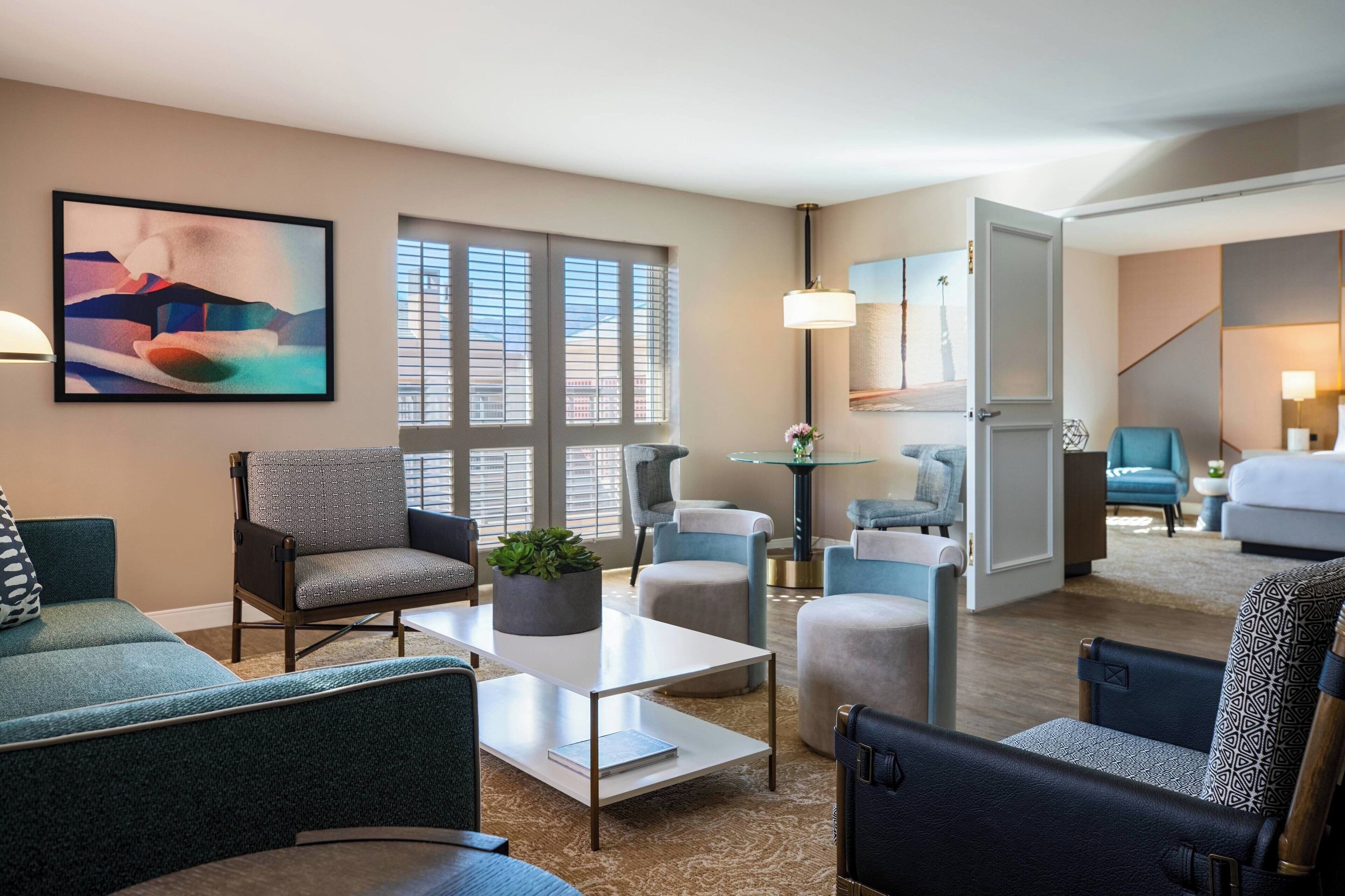 Una habitación de hotel moderna con una zona de estar, una mesa de comedor y una escalera que conduce a otra habitación.