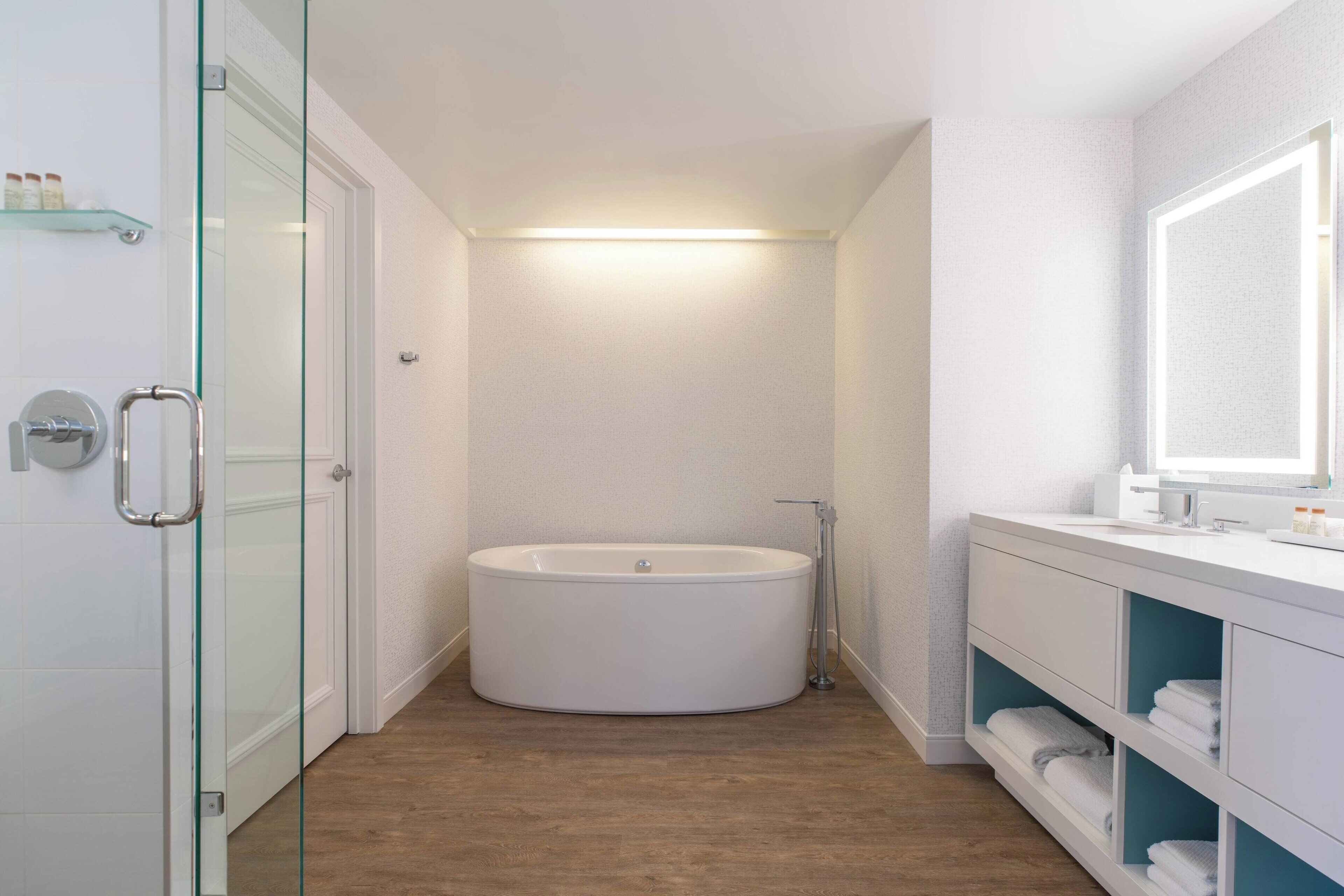 A modern bathroom with a freestanding bathtub, a glass shower enclosure, and a vanity with a mirror.
