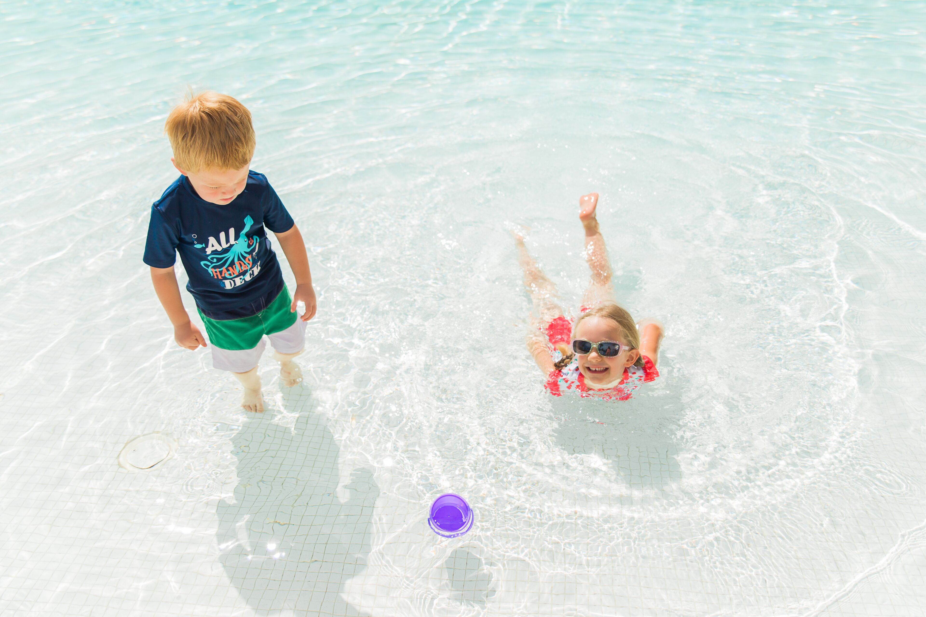 Deux enfants dans une piscine à l’eau claire.