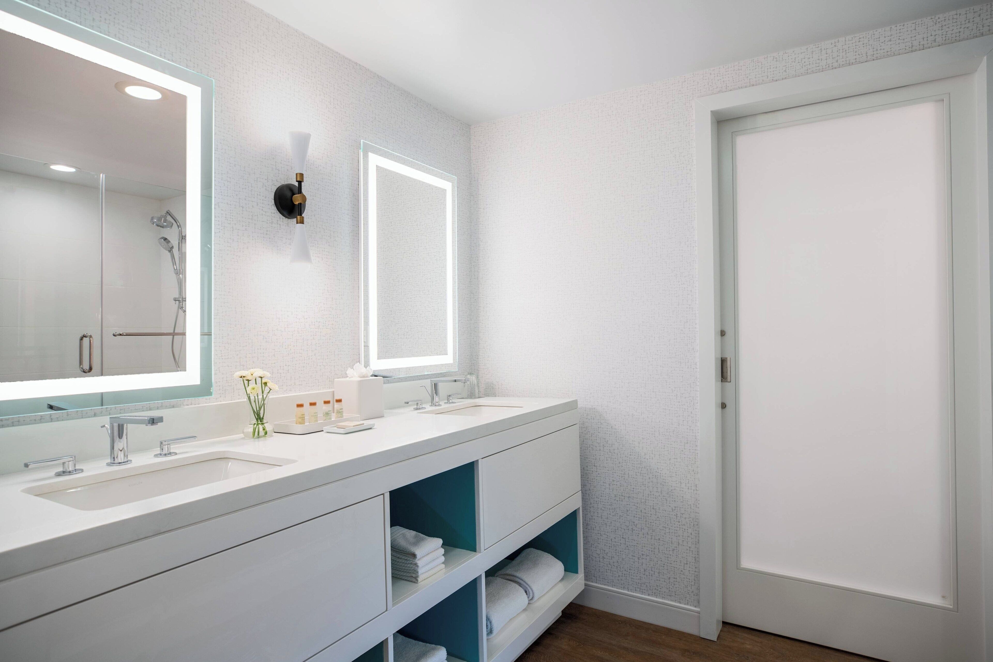 Un bagno moderno con uno specchio grande, due lavabi e una doccia.