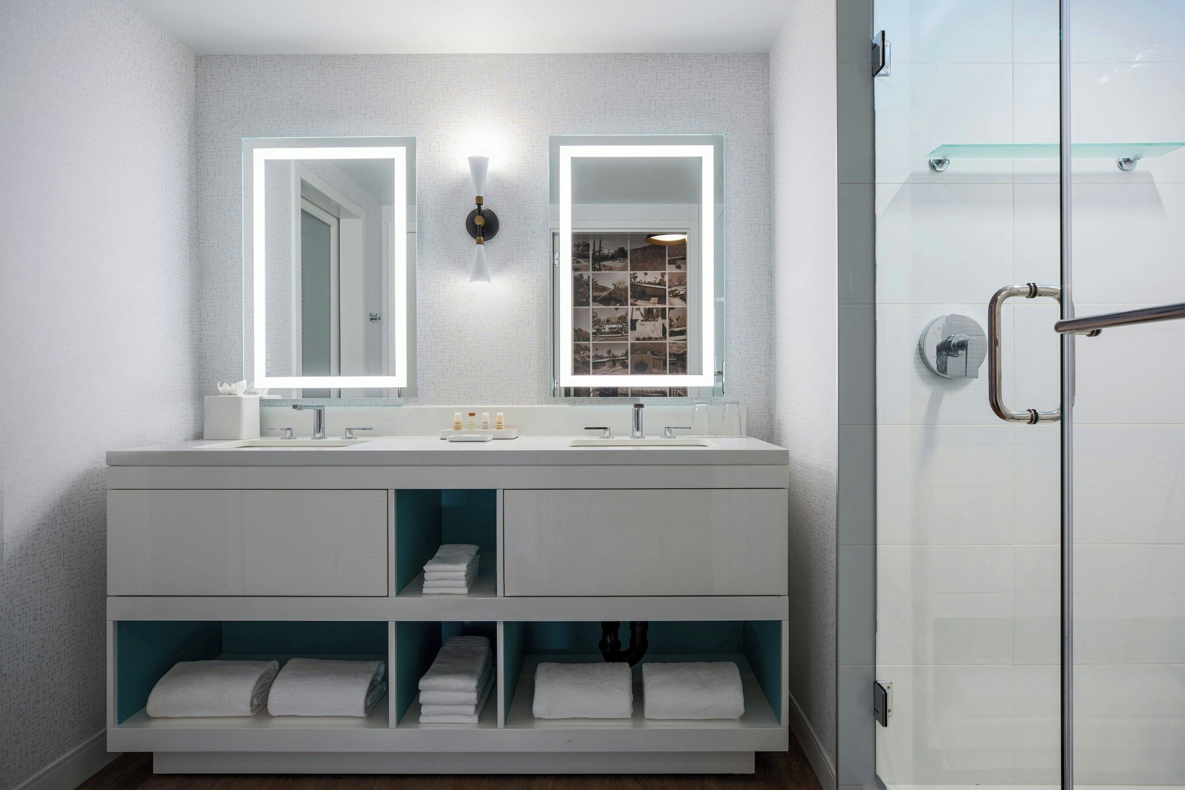 Une salle de bain moderne avec deux lavabos, un grand miroir et une douche à l’italienne.