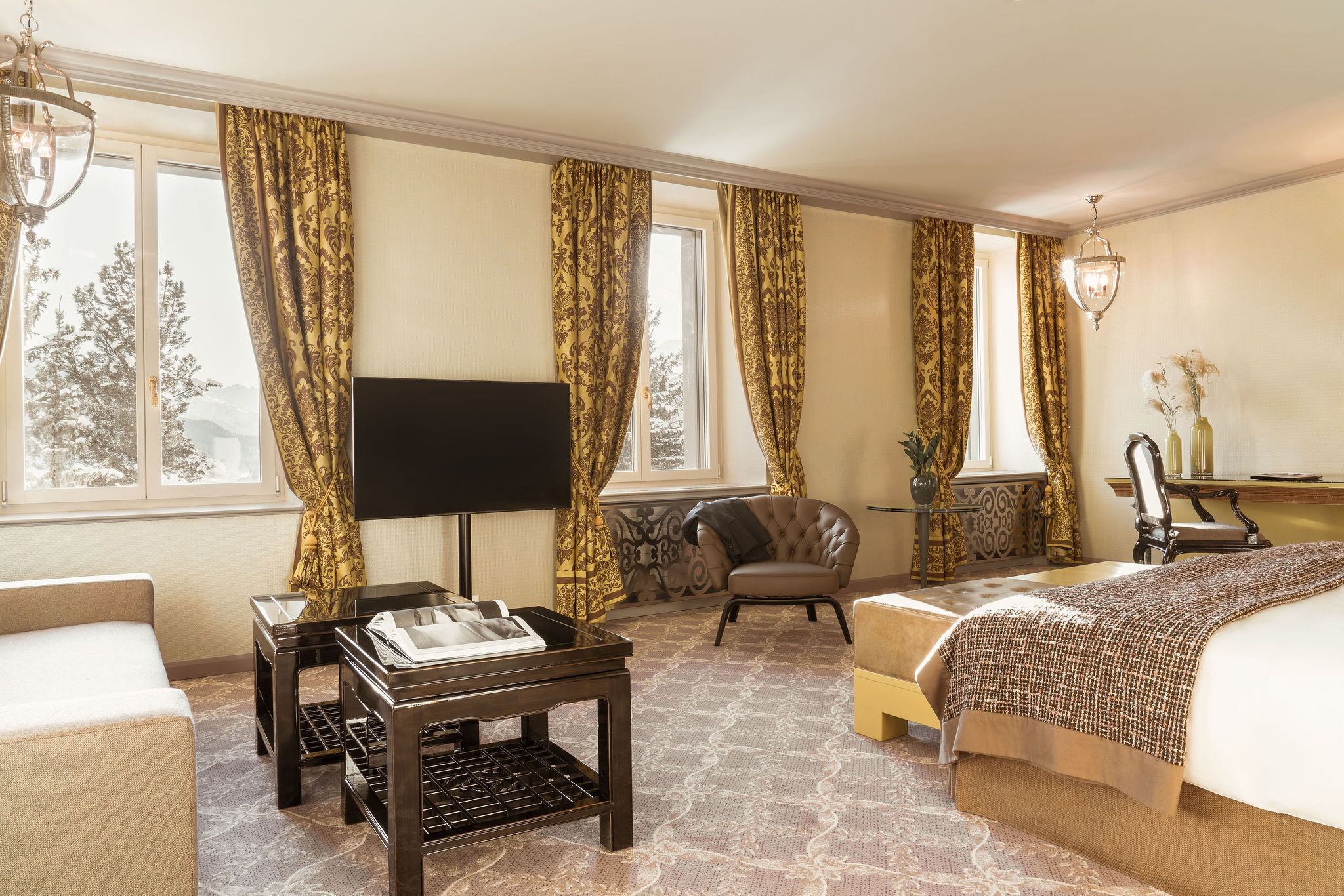A hotel room with a bed, a TV, a desk, a chair, and a window with curtains.
