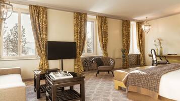A hotel room with a bed, a TV, a desk, a chair, and a window with curtains.