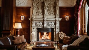A room with a fireplace, leather sofas, a coffee table, and a lamp.