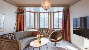 Un salon moderne avec un canapé, une table basse ronde ornée de fleurs, un fauteuil et un grand écran de télévision.