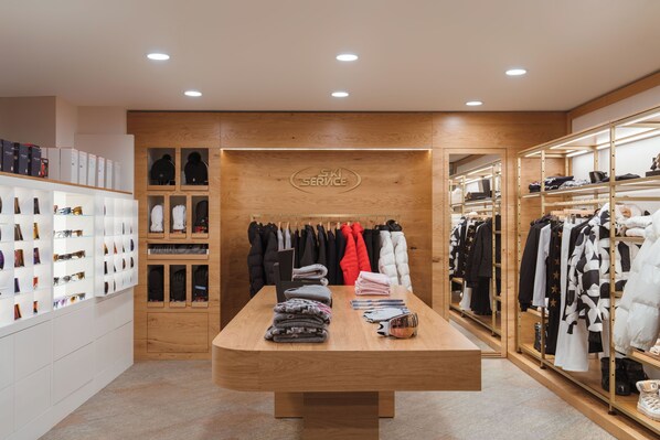 A clothing store with a wooden interior, shelves with folded clothes, and a display table with folded garments.