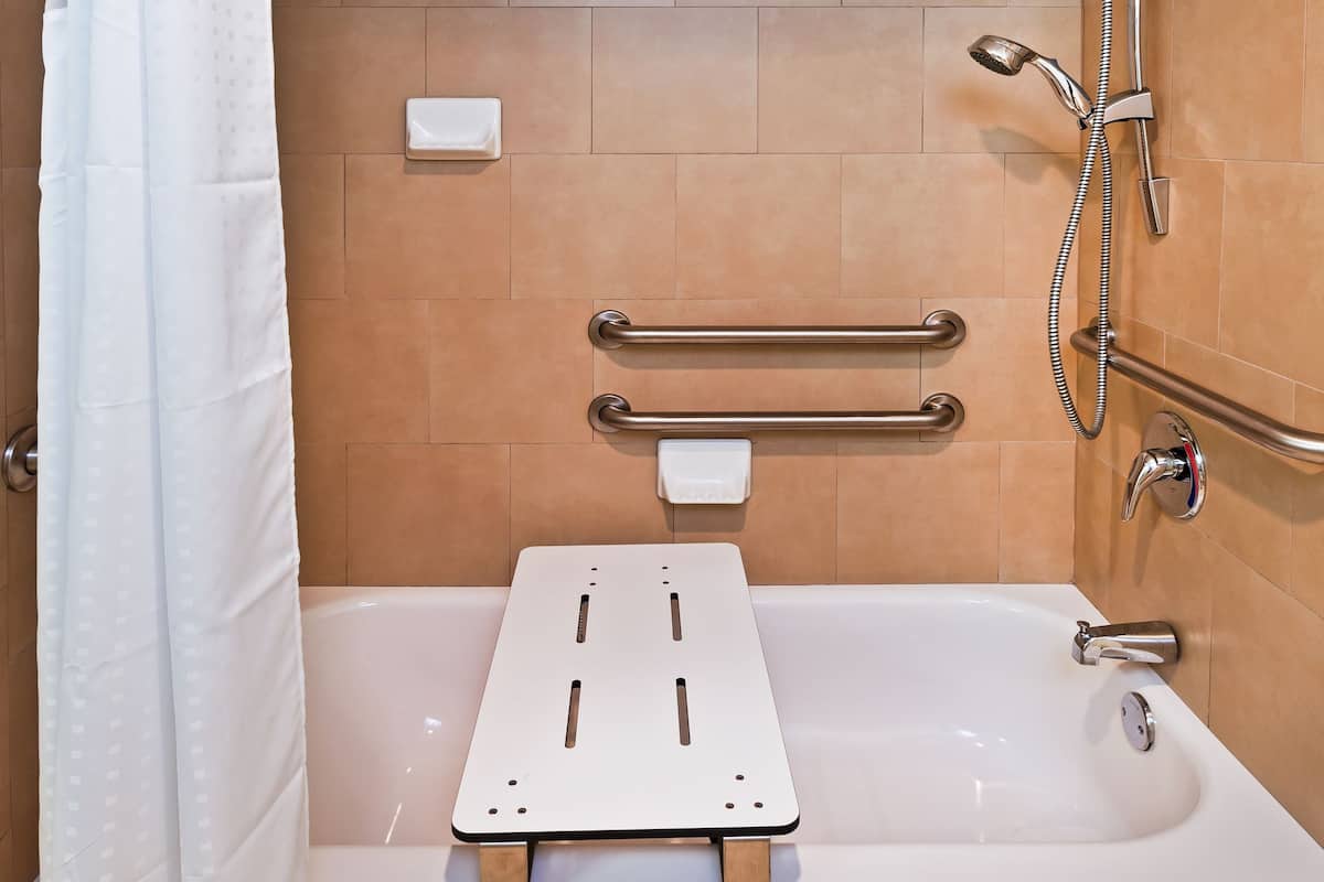 Un baño moderno con bañera, ducha y barras de apoyo.