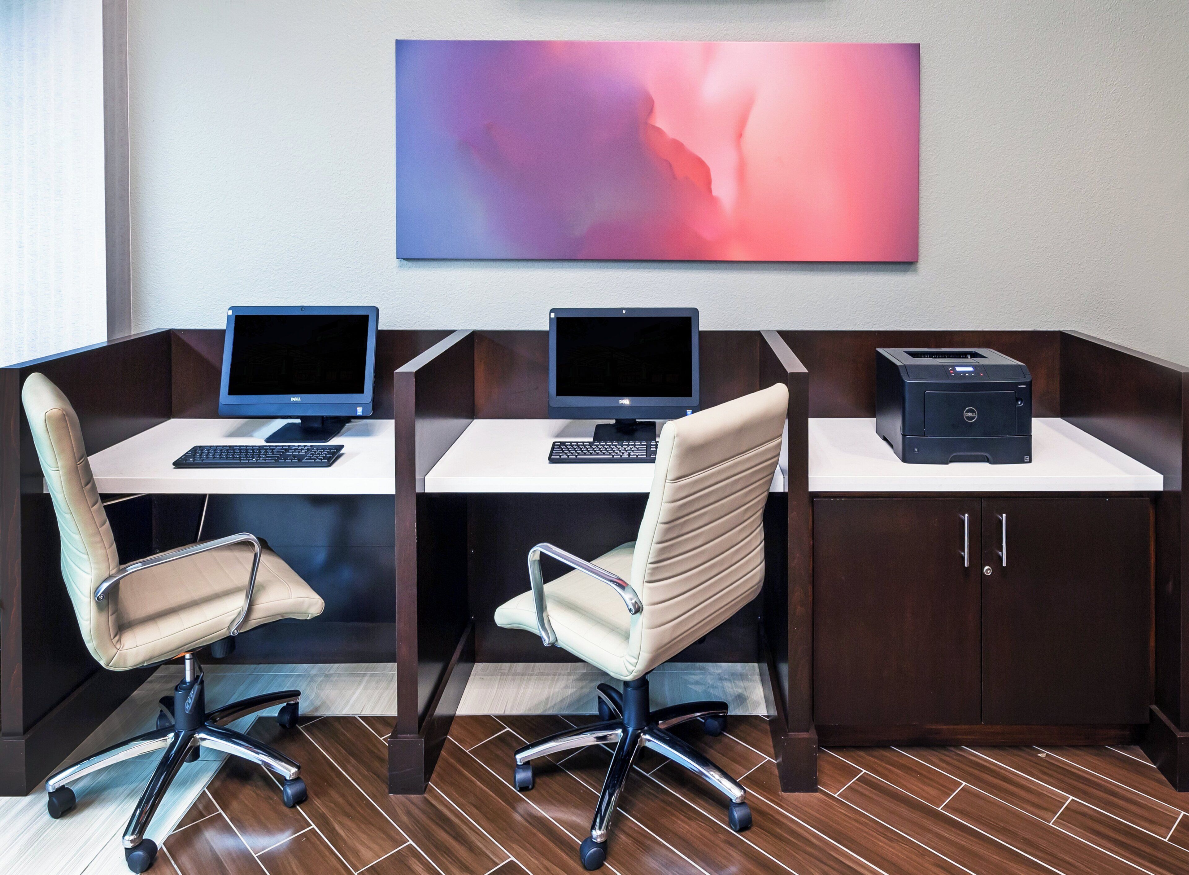 Un espace de bureau moderne avec deux bureaux, chacun équipé d’un ordinateur et d’un clavier, et une imprimante située à droite. Il y a deux chaises de bureau, une sur chaque bureau.