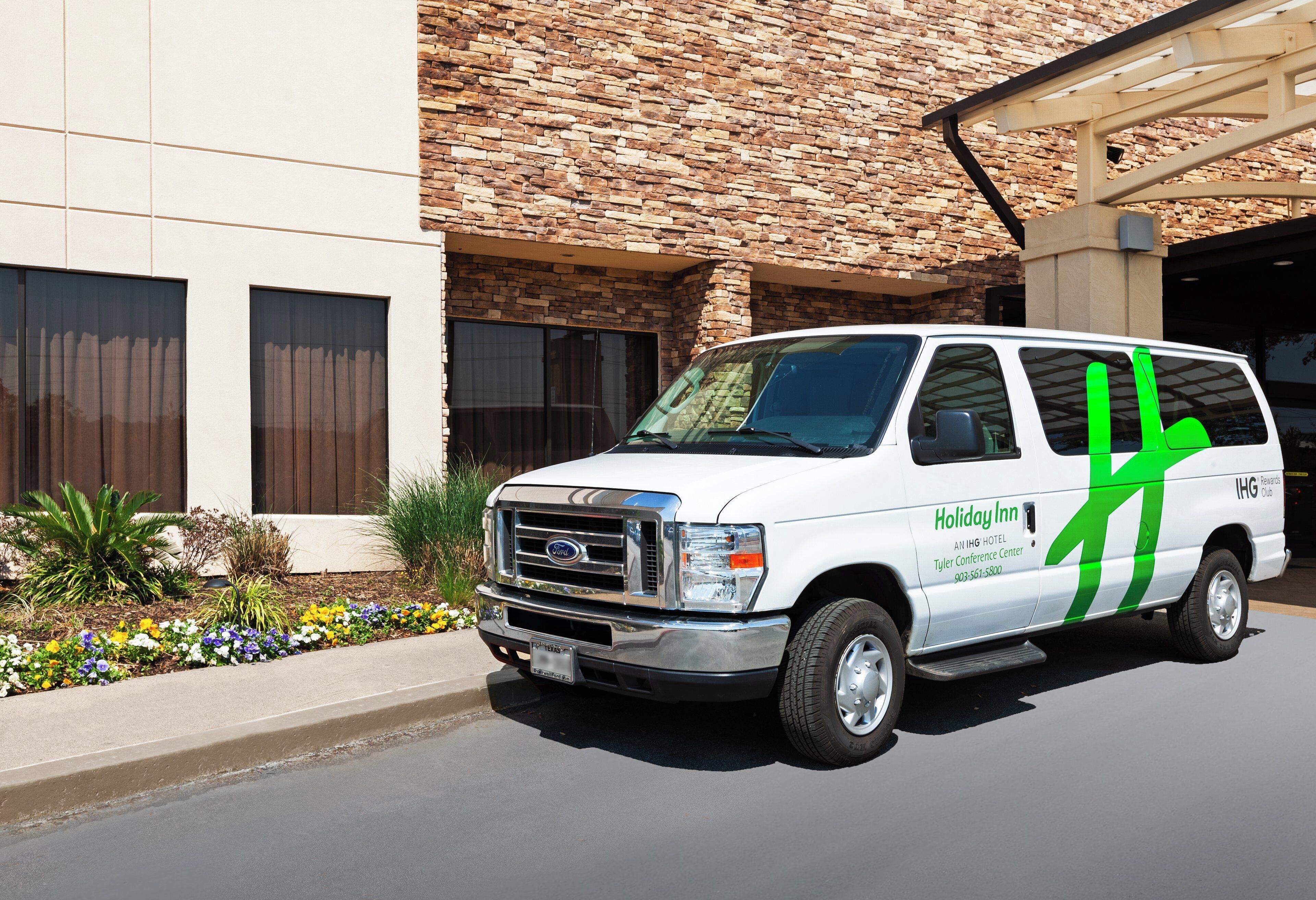 A white van with green stripes parked in front of a building with a stone facade.