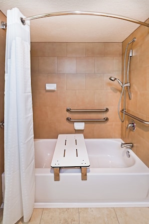 A bathroom with a bathtub, shower, and grab bars.