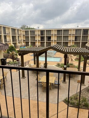 A hotel courtyard with outdoor seating, a pool, and a multi-story building with balconies. - Holiday Inn Tyler-Conference Center by IHG (Tyler)