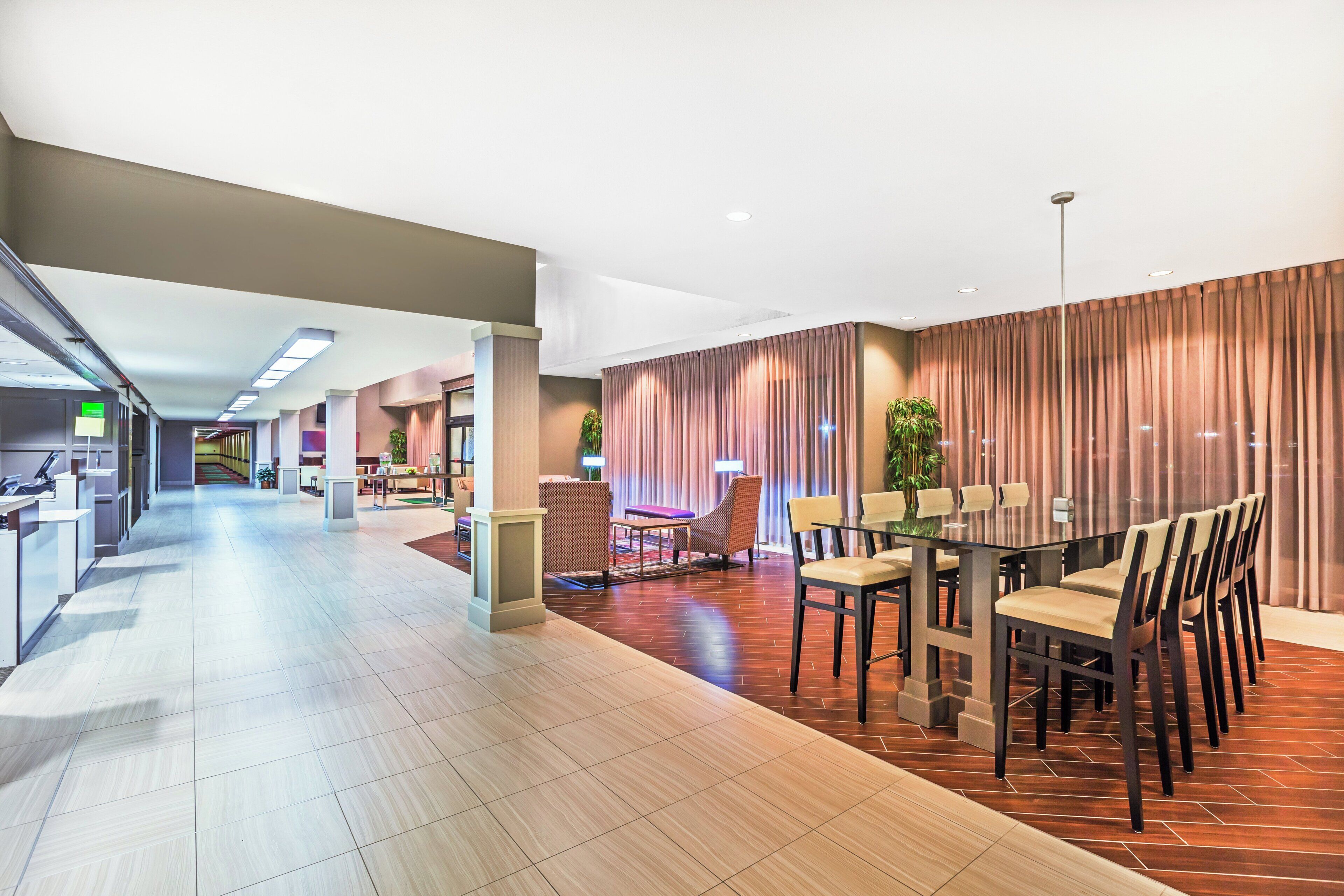Eine moderne Hotelhalle mit Rezeption, Sitzgelegenheiten und einem Essbereich.