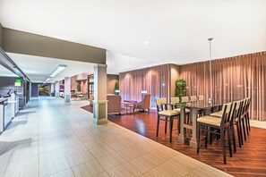 A modern hotel lobby with a reception desk, seating area, and a dining space. - Holiday Inn Tyler-Conference Center by IHG (Tyler)