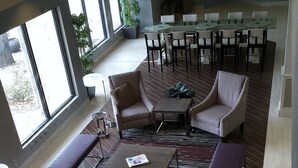 A spacious indoor area with a large dining table, several chairs, and a seating area with sofas and a coffee table. - Holiday Inn Tyler-Conference Center by IHG (Tyler)