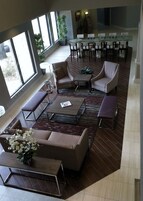 Un espacio interior amplio con una gran mesa de comedor, varias sillas y una zona de estar con sofás y una mesa baja.