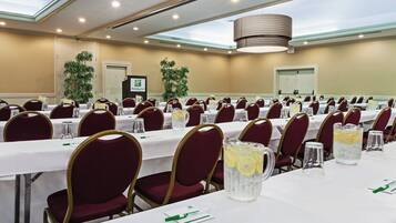 A conference room with multiple tables, chairs, and a Holiday Inn sign.