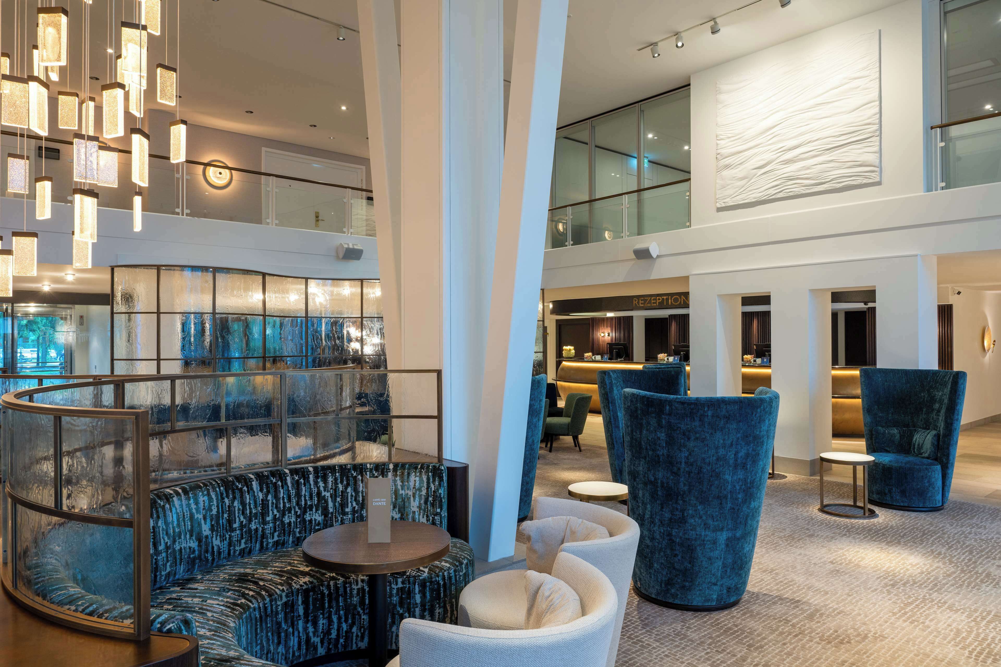 A modern hotel lobby with a glass railing, seating areas, and a reception desk.