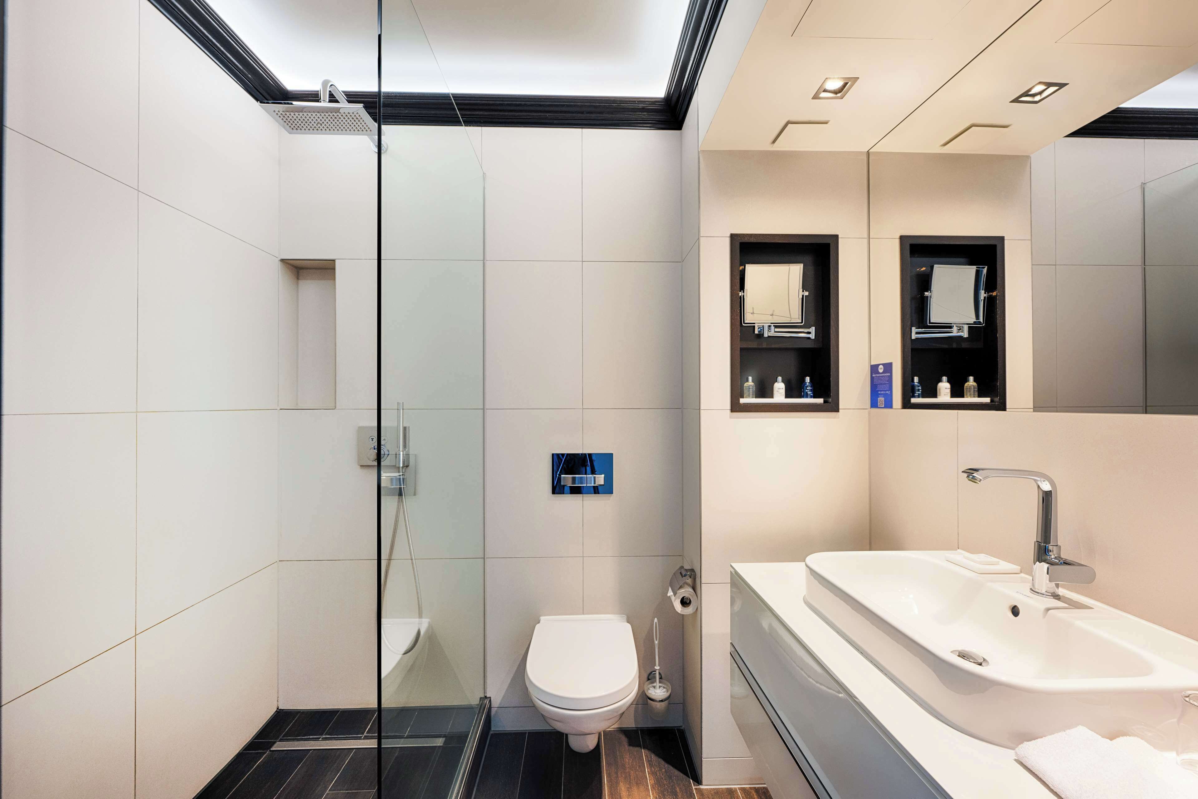 Un baño moderno con cabina de ducha de vidrio, inodoro, lavabo y espejo.