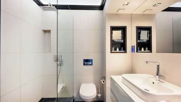 Un baño moderno con cabina de ducha de vidrio, inodoro, lavabo y espejo.
