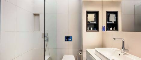 Un baño moderno con cabina de ducha de vidrio, inodoro, lavabo y espejo.