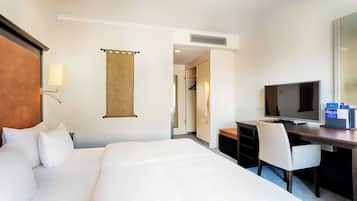 Une chambre d’hôtel avec un grand lit, un bureau avec une télévision, une chaise et une armoire.