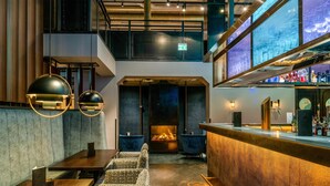 A modern bar area with seating, a fireplace, and a bar counter. - Radisson Blu Senator Hotel (Lübeck)