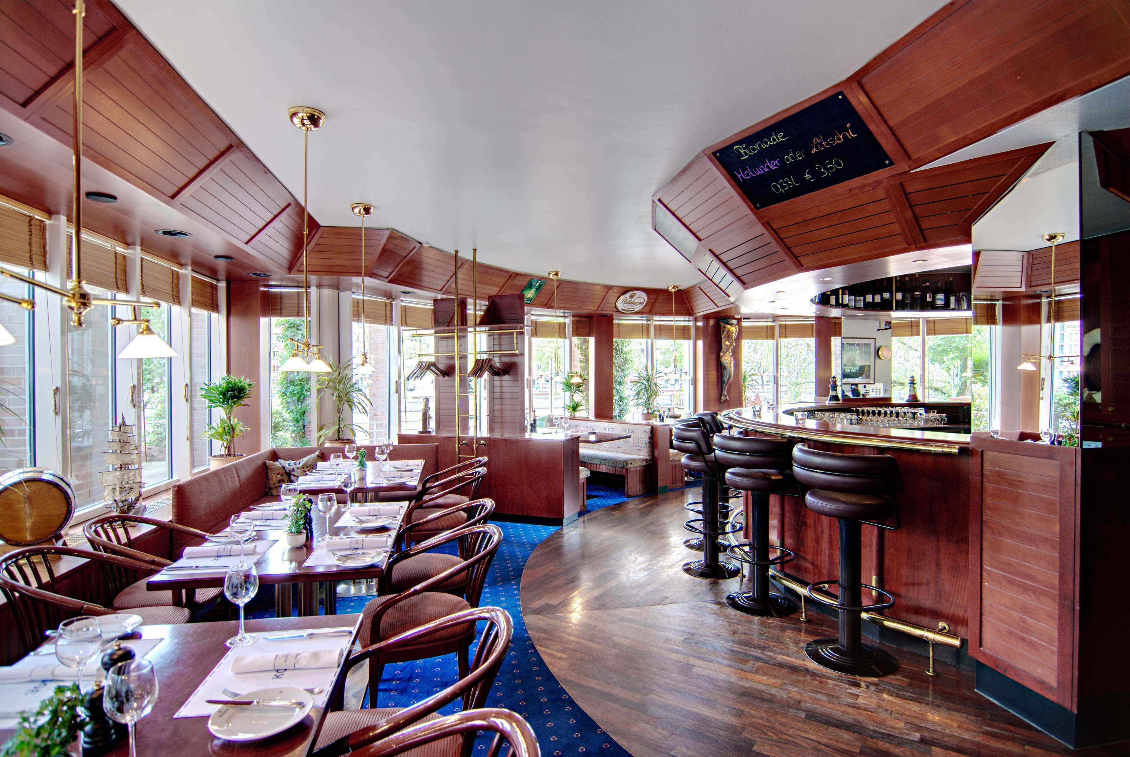 Un restaurant avec des murs lambrissés, de grandes fenêtres et un coin bar.
