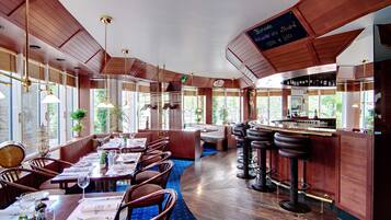 Un restaurant avec des murs lambrissés, de grandes fenêtres et un coin bar.