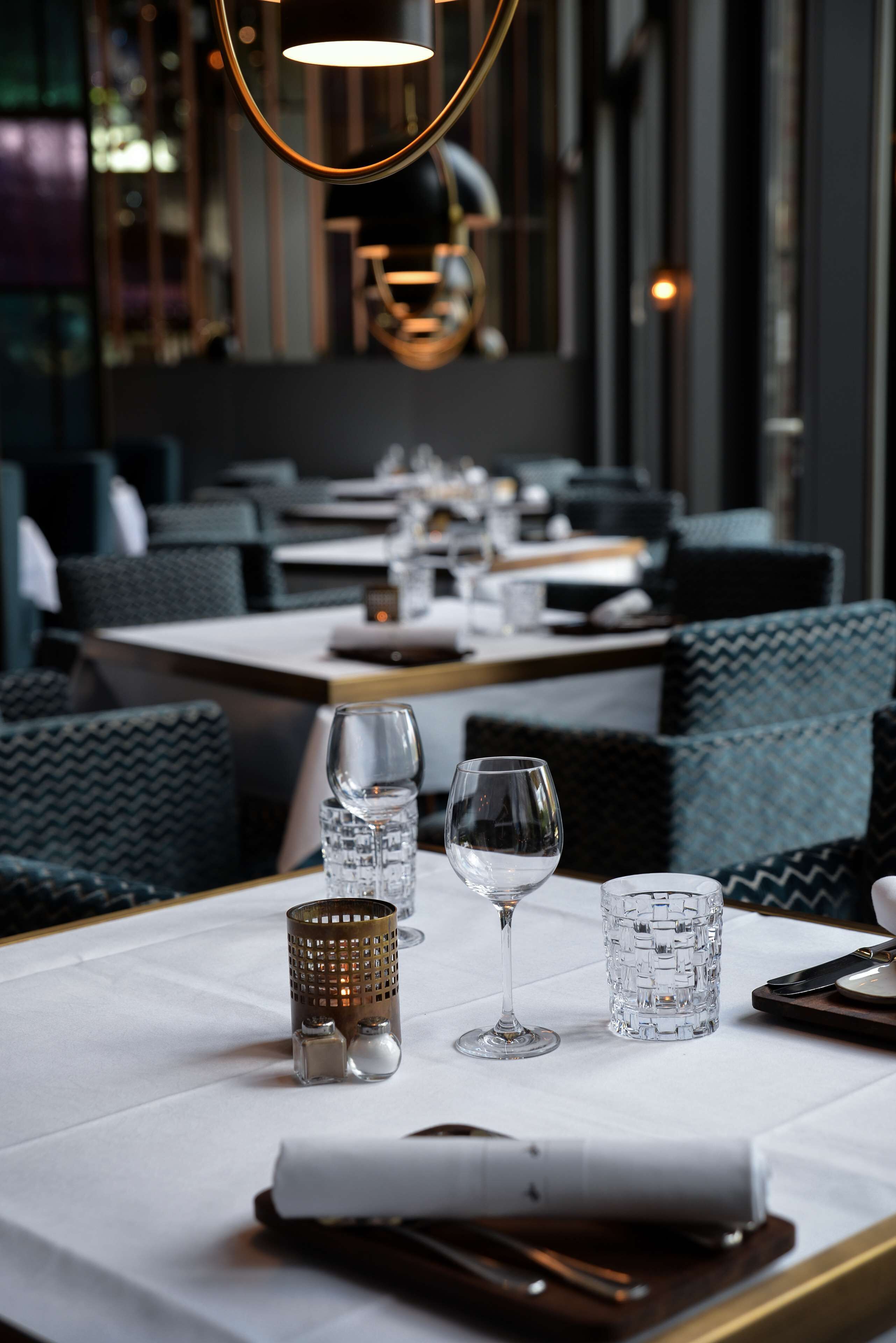 A restaurant setting with a table set for dining, including glasses, cutlery, and a menu.
