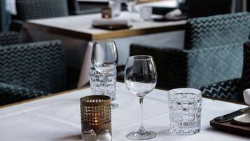 A restaurant setting with a table set for dining, including glasses, cutlery, and a menu.