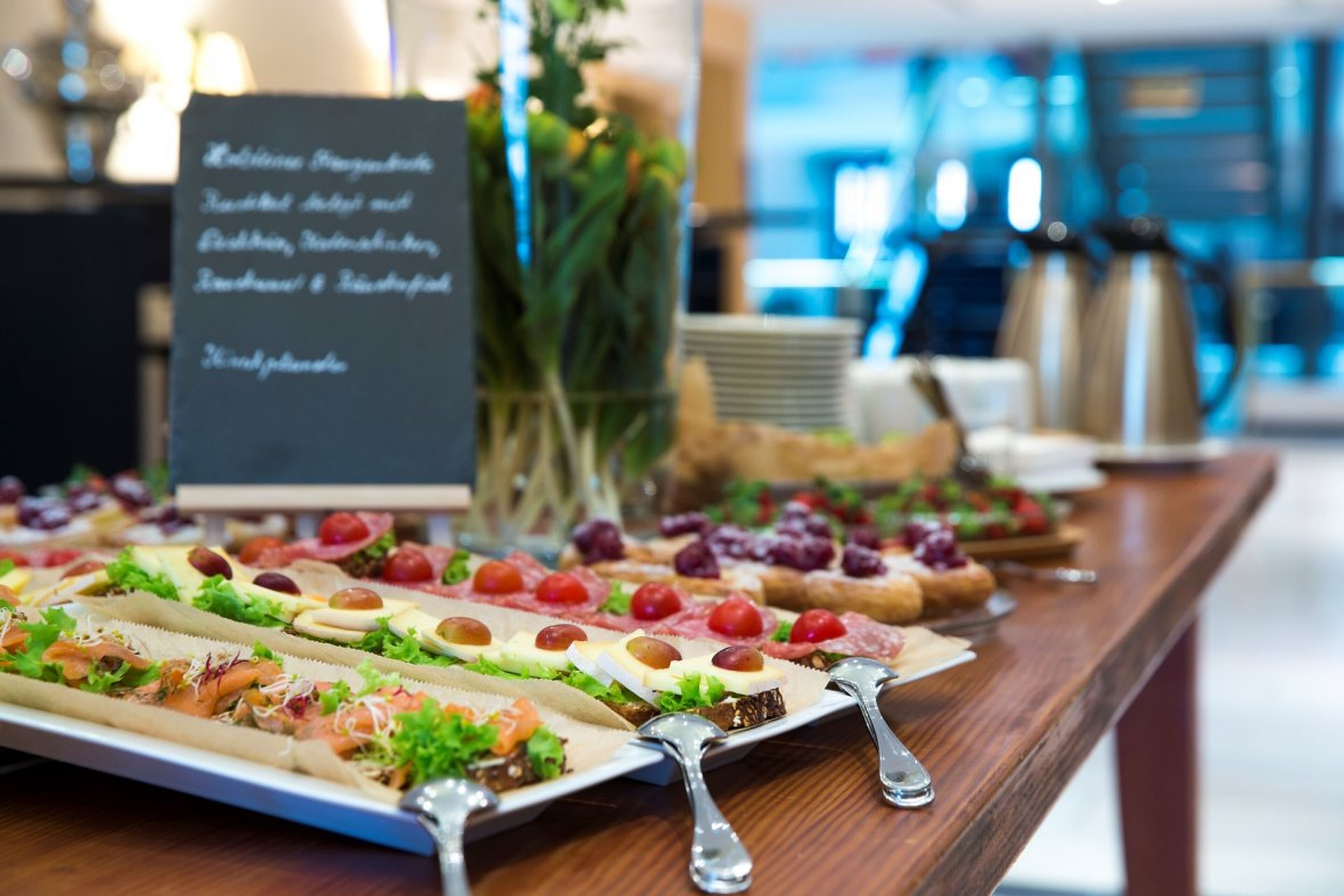 Mesa de buffet com diversos alimentos e um aviso listando o cardápio.