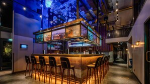 A bar area with a central bar counter, multiple stools, and a ceiling with illuminated spherical decorations. - Radisson Blu Senator Hotel (Lübeck)
