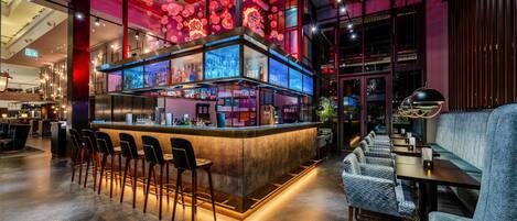A modern bar area with a bar counter, stools, and a seating area with tables and chairs.