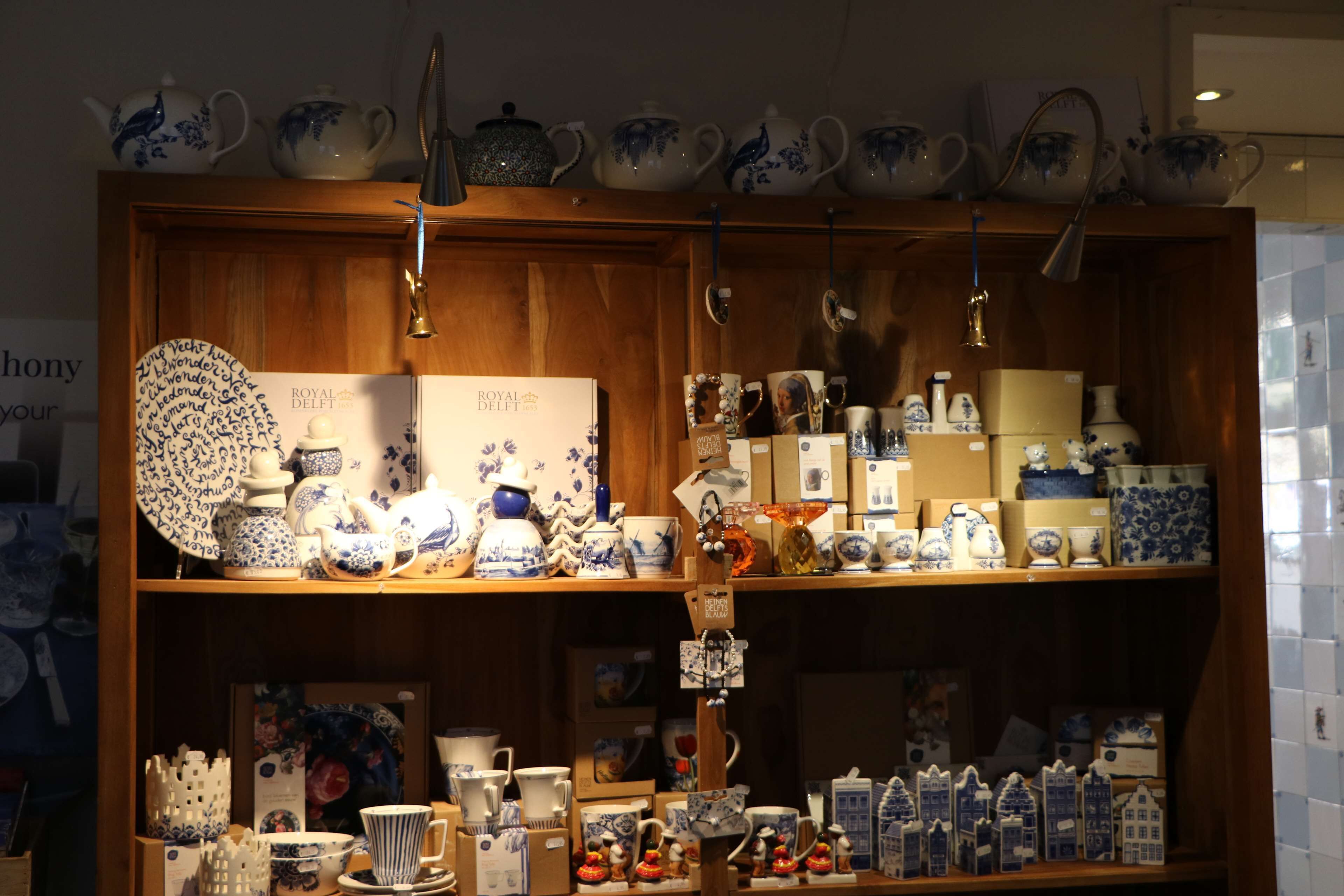 Een presentatie van diverse keramieken objecten, waaronder theepotten, kopjes en decoratieve stukken, gerangschikt op planken in een winkel.