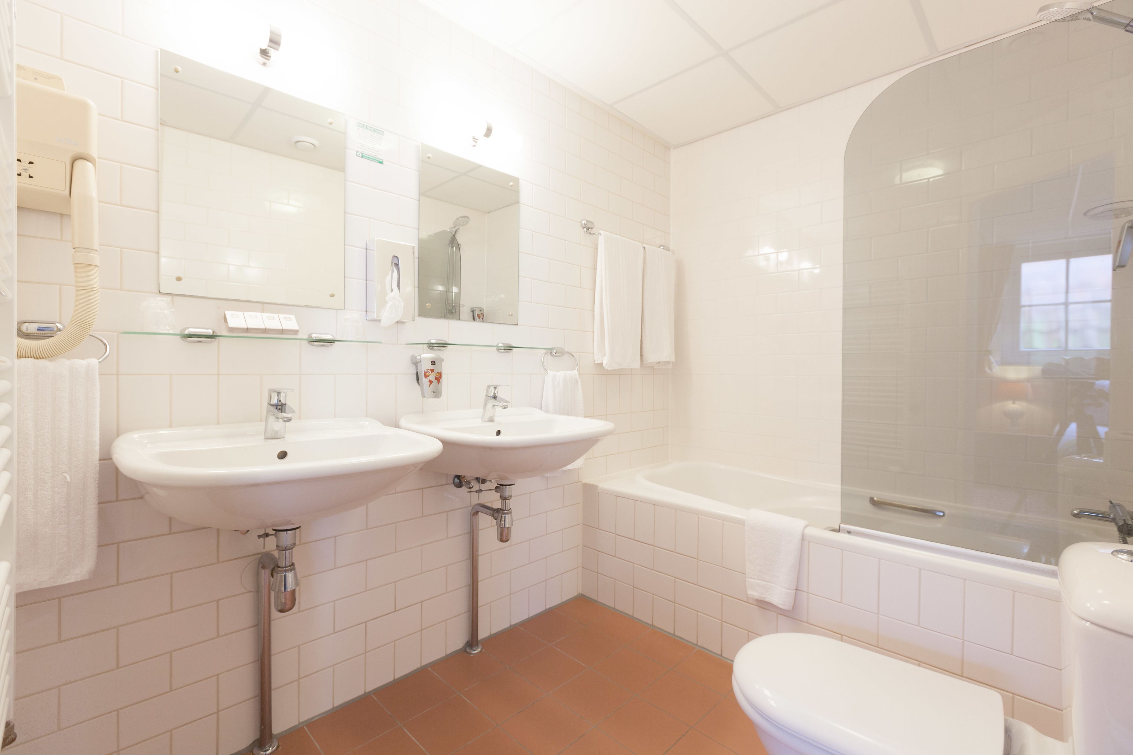 A modern bathroom with two sinks, a bathtub, and a glass-enclosed shower.