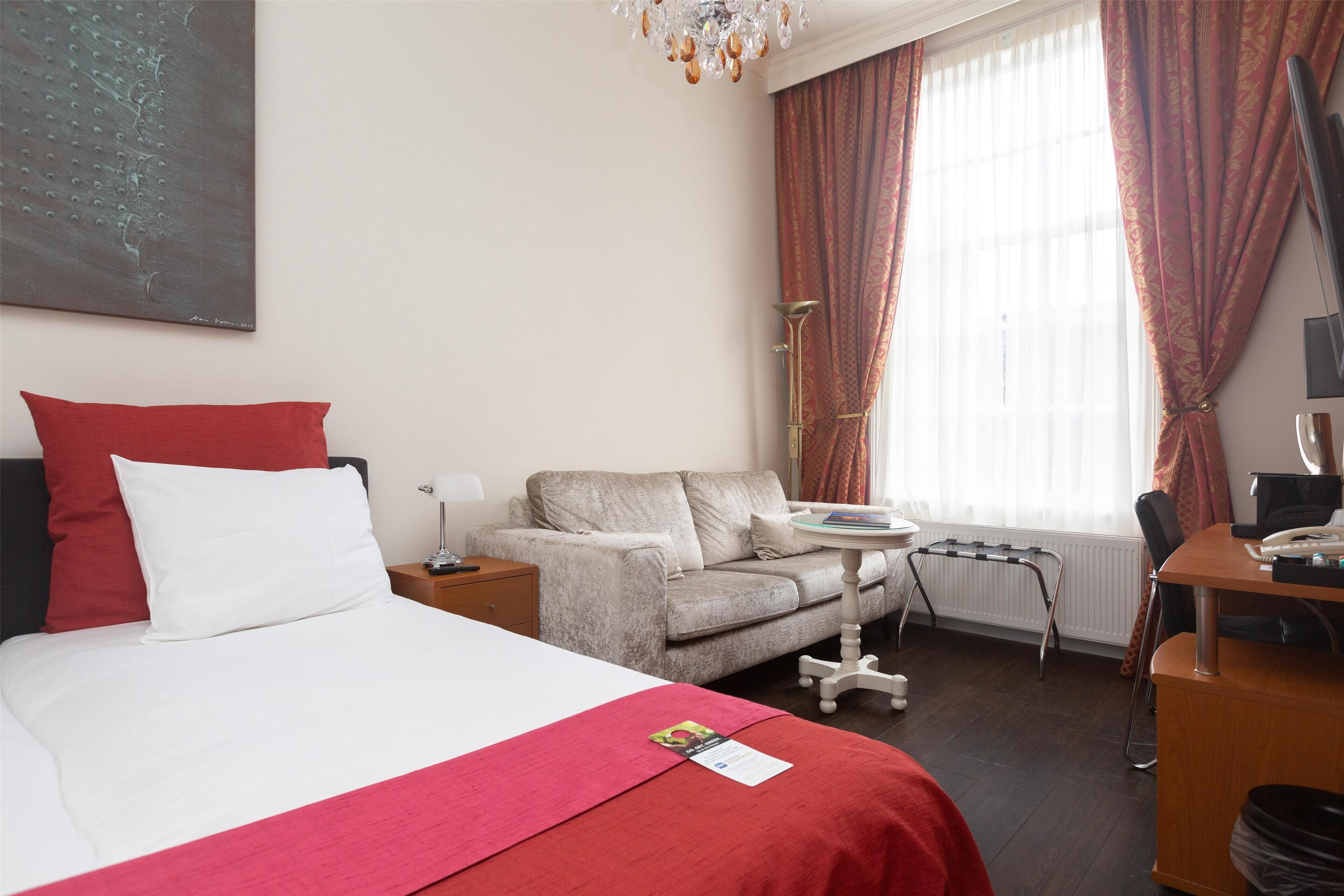 Een hotelkamer met een bed, een bank, een bureau en een stoel.
