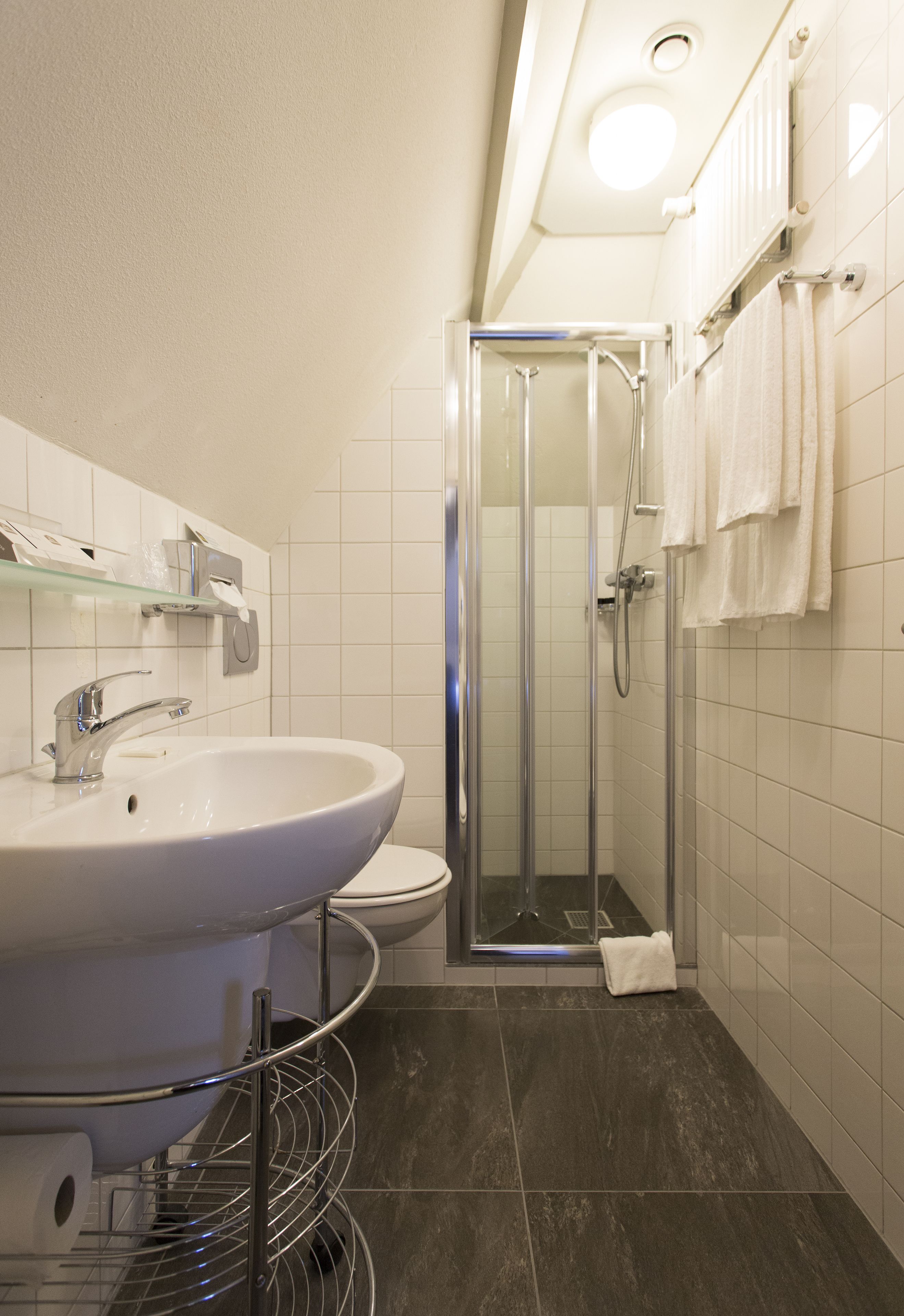 Een moderne badkamer met een wit wastafelmeubel, toilet en douchecabine met glazen wanden.