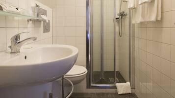 Een moderne badkamer met een wit wastafelmeubel, toilet en douchecabine met glazen wanden.