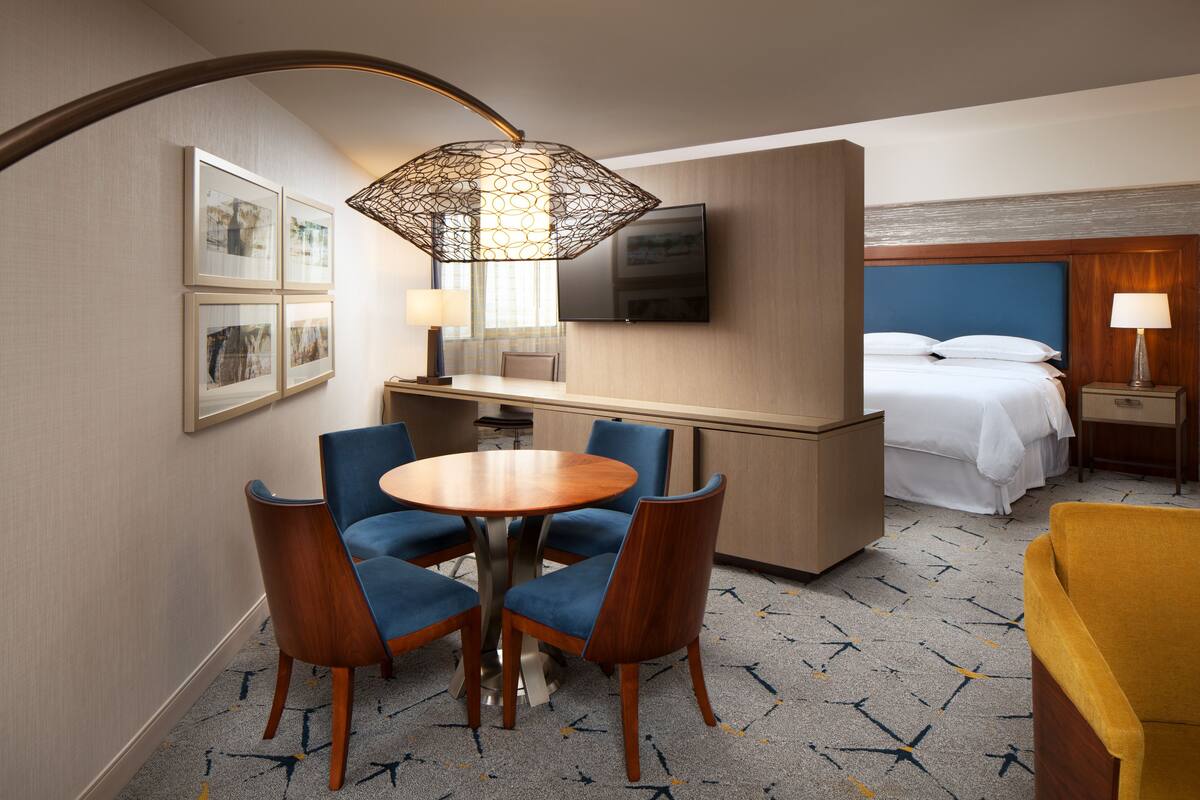 Une chambre d’hôtel avec un lit, un bureau, une chaise, une table et un téléviseur.