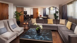 A modern living room with a sectional sofa, two armchairs, a coffee table, and a dining area in the background.