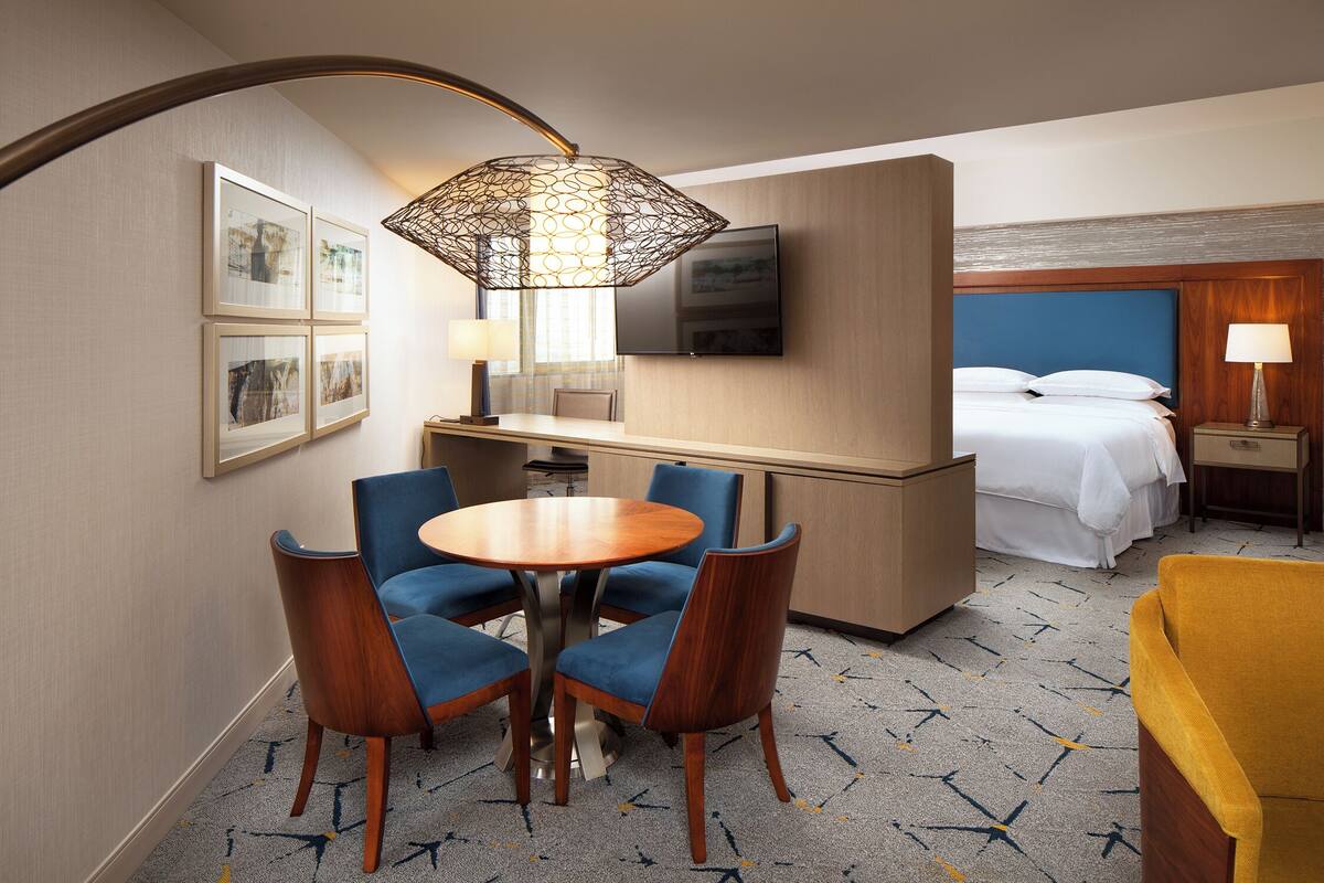 Une chambre d’hôtel comprenant un coin repas, un lit, une télévision et un bureau.